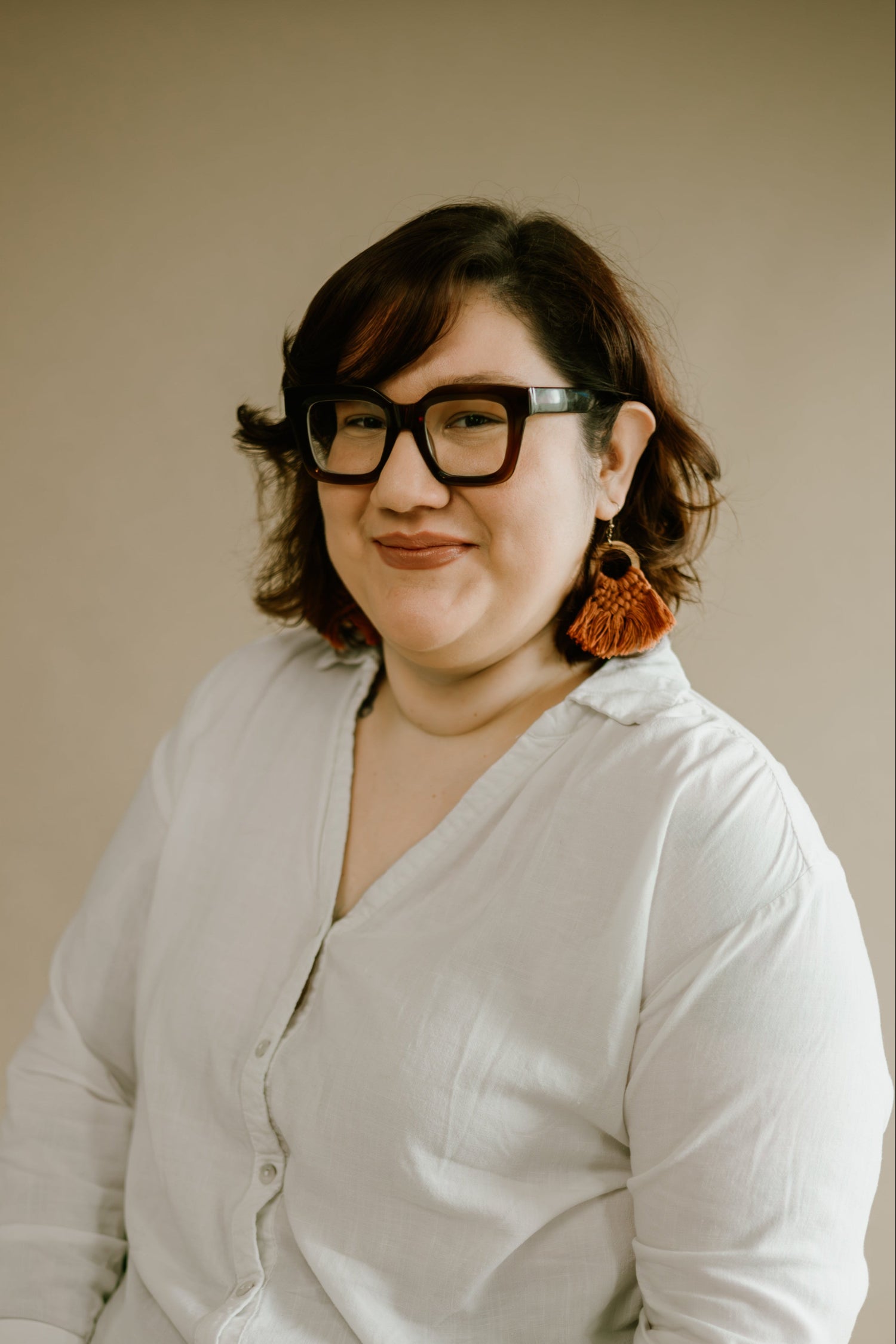 Woman wearing a light gray cardigan against a beige background